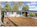 Single-story home with white and dark gray exterior, trees, and fallen leaves at 1566 Sagewood Cir, Stone Mountain, GA 30083