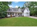 Picturesque home exterior with a covered front porch, surrounded by greenery, and an attached garage at 4378 Ridge Ct, Loganville, GA 30052