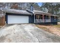 Front view of a charming ranch home with a white garage door and a spacious driveway at 155 Meadowbrook Dr, Mcdonough, GA 30253