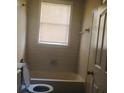 Simple bathroom with a bathtub, toilet, and window at 309 Fletcher Sw St, Atlanta, GA 30315