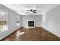 Spacious living room with wood-look flooring, a fireplace, a ceiling fan, and large windows at 3075 Heather Stone Way, Lawrenceville, GA 30043