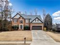 Inviting two-story brick home with a well-maintained lawn, driveway, and attached two-car garage at 8415 River Walk Lndg, Suwanee, GA 30024