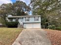 Blue siding home with a two-car garage and mature trees at 1435 Winchester Trl, Riverdale, GA 30296