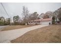 Gray ranch home with red metal roof, driveway, and mature trees at 70 E Honeysuckle Ln, Carrollton, GA 30116
