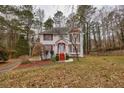 Two-story house with red accents, driveway, and mature trees in the yard at 308 Mainsail Ln, Woodstock, GA 30189