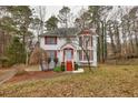Two-story house with red accents, driveway, and mature trees in the yard at 308 Mainsail Ln, Woodstock, GA 30189