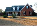 Brick home with dormer windows, porch, and landscaped yard at 321 Whitney Ln, Mcdonough, GA 30253