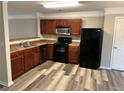 Kitchen with dark wood cabinets, black appliances, and laminate flooring at 837 Crestwell Sw Cir, Atlanta, GA 30331