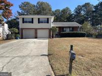 Brick house exterior with a two-car garage and well maintained lawn at 5878 Nell Ln, Ellenwood, GA 30294