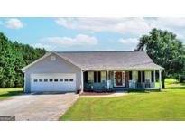 Ranch style home with attached garage and rocking chairs on the front porch at 1042 Harbins Rd, Dacula, GA 30019
