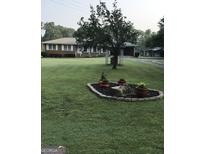 Brick ranch house with a landscaped front yard and large tree at 121 Rowan Rd, Ellenwood, GA 30294