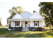 White farmhouse with a front porch, landscaping, and large yard at 10 Maranatha Rd, Mcdonough, GA 30252