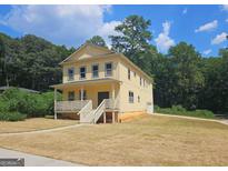 Two-story yellow house with a front porch and landscaped yard at 321 Seventh Ave, Scottdale, GA 30079