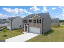 Two-story house with gray and beige siding, a two-car garage, and a landscaped yard at 619 Whitman Ln # 2200, Stockbridge, GA 30281