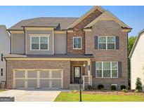 Two-story brick house with a large front yard and three car garage at 3290 Stock Saddle Pl, Cumming, GA 30040