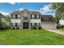 Two-story house with stone accents, double garage, and landscaped lawn at 1125 Misty Meadows Ln, Hampton, GA 30228
