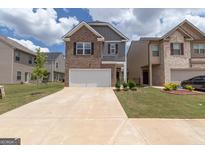 Two-story brick home with a two-car garage and landscaped lawn at 1705 Labonte Pkwy, Mcdonough, GA 30253
