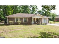 Brick ranch house with a covered porch and spacious yard at 140 Grove Creek Dr, Locust Grove, GA 30248