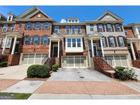 Three-story townhouses with brick and stone exteriors, two-car garages and brick walkways at 1656 Woodbridge Ne Ln, Atlanta, GA 30329