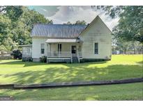 Charming white farmhouse with a wraparound porch at 27 Smith St, Locust Grove, GA 30248
