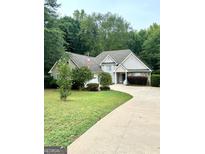 Beige two-story house with a gray roof, driveway, and American flag at 345 Alcovy Cir, Covington, GA 30014