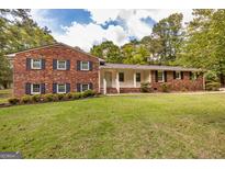 Brick rancher with a covered entry, well-manicured lawn, and mature trees at 8289 Lake View Ter, Riverdale, GA 30274