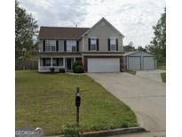 Two-story house with attached garage and well-maintained lawn at 5496 Vanity Joys Ln, Ellenwood, GA 30294