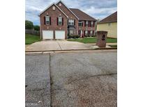 Brick house with two-car garage and landscaped yard at 1158 Folkstone Dr, Mcdonough, GA 30253