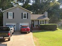 Gray house with two-car garage and landscaped yard at 110 Gwenellen Dr, Locust Grove, GA 30248