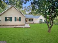 House exterior featuring a beige vinyl siding, green trim, and a well-maintained lawn at 205 Creekside Way, Mcdonough, GA 30252