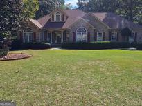 Brick home with a well-maintained lawn and landscaping at 8110 Lakemont Close, Mcdonough, GA 30253