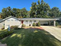 Brick ranch home with covered porch, carport, and well-manicured lawn at 3107 Cherry Blossom Ln, East Point, GA 30344