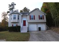Tan two-story house with red door and attached two-car garage at 6995 Pine Shadow Way, Winston, GA 30187