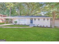 Charming ranch home with a white brick facade, landscaped lawn, and a blue front door at 1370 David Cir, Decatur, GA 30032
