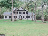 Two story home with white brick exterior, black shutters, and a manicured lawn at 275 Allie Dr, Mcdonough, GA 30252