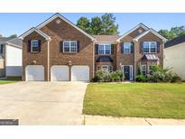 Brick two-story house with three-car garage and landscaped lawn at 326 Cog Hill Dr, Fairburn, GA 30213