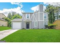 Two-story house with gray siding, a double-car garage, and a well-maintained lawn at 6235 Creekford Ln, Lithonia, GA 30058
