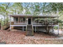 Gray house with wooden stairs and deck, surrounded by trees at 215 Shadow Wood Dr, Douglasville, GA 30134