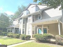 Two-story townhome with gray siding, teal door, and manicured landscaping at 6390 Arbor Ln, Morrow, GA 30260
