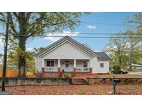 Charming white house with a brick base, porch, and mature trees in the yard at 331 North Ave, Villa Rica, GA 30180