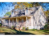 Tan house with a wraparound porch and rocking chairs, surrounded by trees at 145 West Honeysuckle Lane, Carrollton, GA 30116