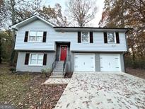 Two-story house with gray siding, red door, and three-car garage at 55 Stone Creek Dr, Covington, GA 30016