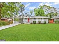 Charming ranch home with a red door, covered porch, and well-maintained lawn at 2057 Sombrero Se Way, Atlanta, GA 30316
