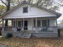White house with gray porch and railings, situated on a lot with trees at 1143 Windsor Sw St, Atlanta, GA 30310