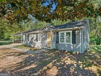 Gray house with a yellow door, surrounded by trees and a yard at 1178 Dallas Hwy, Villa Rica, GA 30180