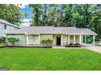 Ranch style home with gray siding, landscaped lawn, and covered patio at 2312 Leslie Brook Dr, Decatur, GA 30035
