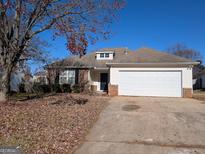 Brick house with attached garage and driveway, surrounded by trees with autumn leaves at 6195 Winston Trce, Mcdonough, GA 30252