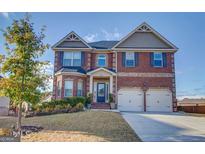 Two-story brick home with a three-car garage and landscaped lawn at 643 Besra Dr, Grayson, GA 30017