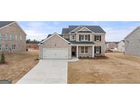 New construction home with brick and siding exterior, front-facing two-car garage, and landscaping at 663 Edgar St # 25, Hampton, GA 30228