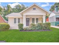 Charming bungalow with white brick exterior, covered porch, and well-manicured lawn at 555 Holly Nw St, Atlanta, GA 30318
